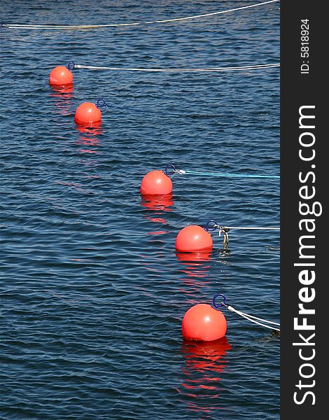 Buoys for small boats. Five orange balls floating in the water