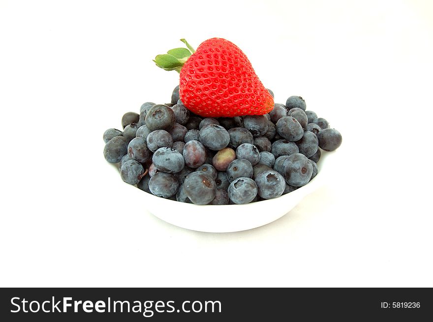 An image of a strawberry on top of a bowl full of fresh blueberries. An image of a strawberry on top of a bowl full of fresh blueberries.