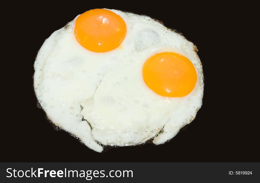 A pair of eggs being cooked. isolated on black.