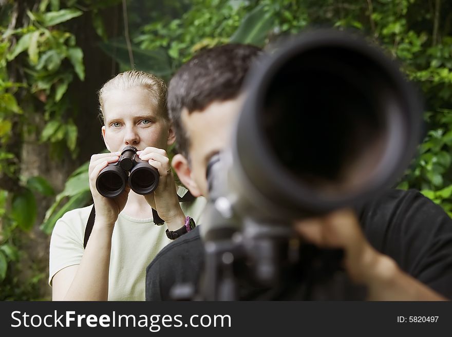 Pretty Woman with Binoculars and Man with Telescope in Rain Forest Jungle