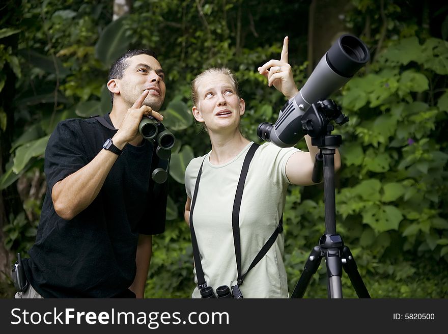 Pretty Woman with Binoculars and Man with Telescope in Rain Forest Jungle