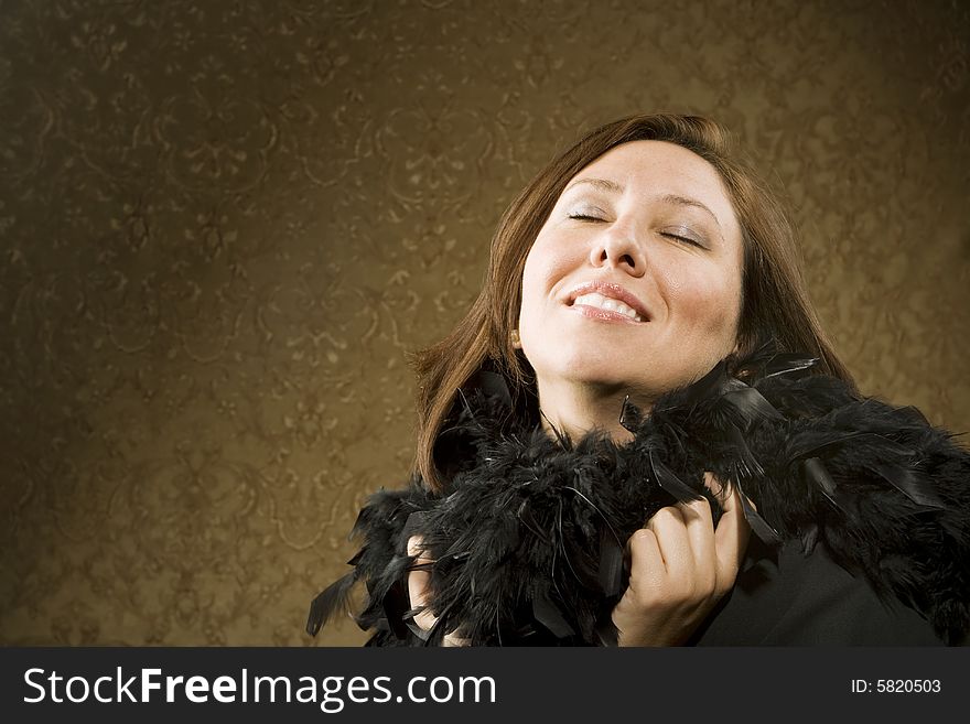 Pretty Hispanic Woman Wearing a Feather Boa in front of Gold Wallpaper. Pretty Hispanic Woman Wearing a Feather Boa in front of Gold Wallpaper