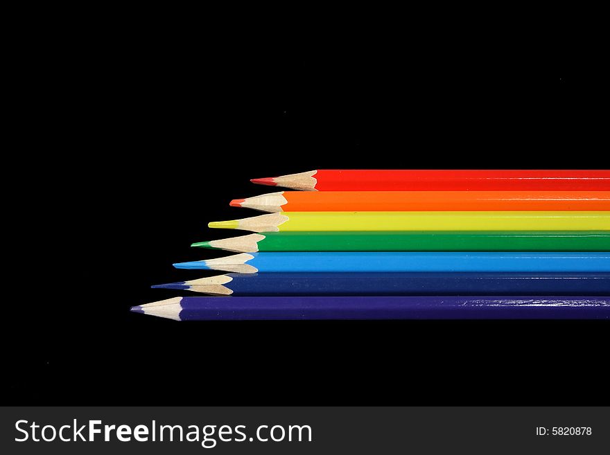 Seven pencils of all colors of a rainbow lay on a black background. Seven pencils of all colors of a rainbow lay on a black background.