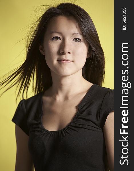 Vertical head ans shoulders portrait of young Asian woman against a yellow background. Vertical head ans shoulders portrait of young Asian woman against a yellow background.