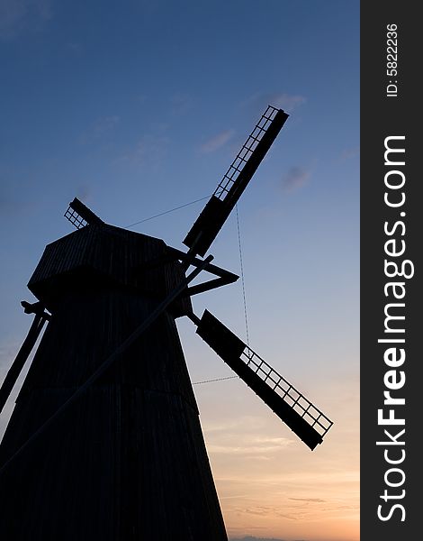 Silhouette of an old windmill on a background of sunset
