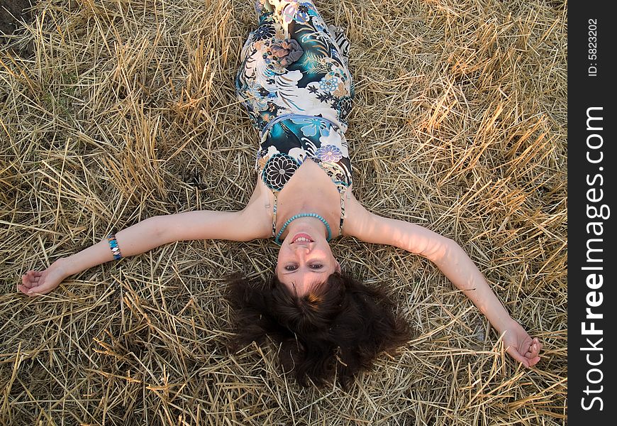 Young lady lying in straw smiling arms outstretched. Young lady lying in straw smiling arms outstretched