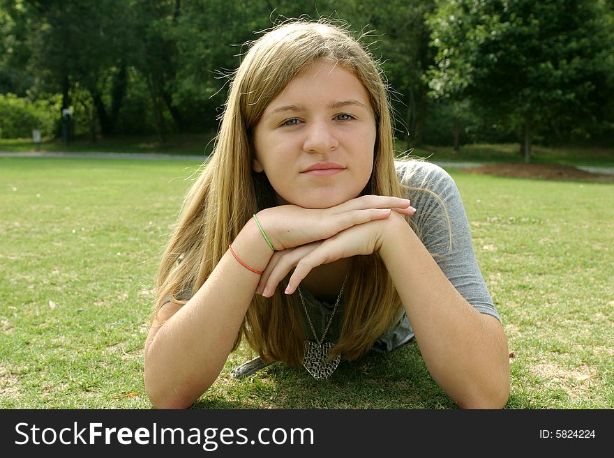 Teenage girl wearing a gray shirt laying in the grass