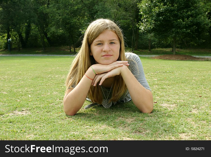 Teenage girl wearing a gray shirt laying in the grass