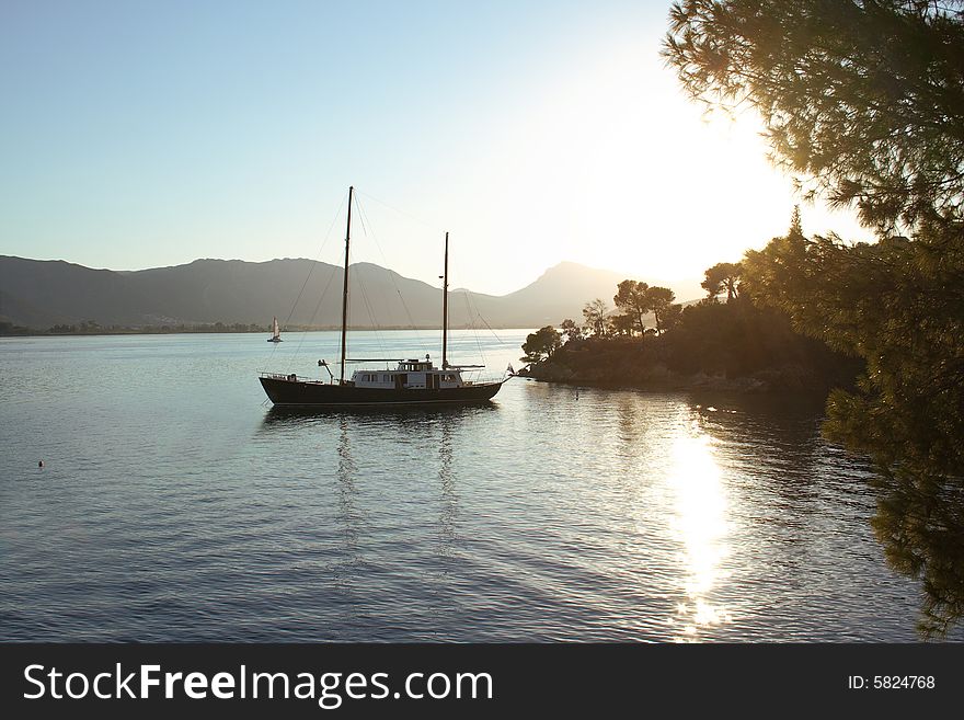 Old wooden yacht over the sunset in a greek island