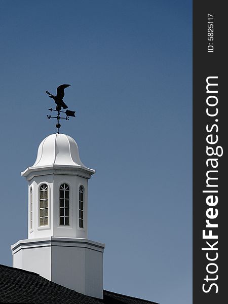 White cupola and weather vane against blue sky. White cupola and weather vane against blue sky.