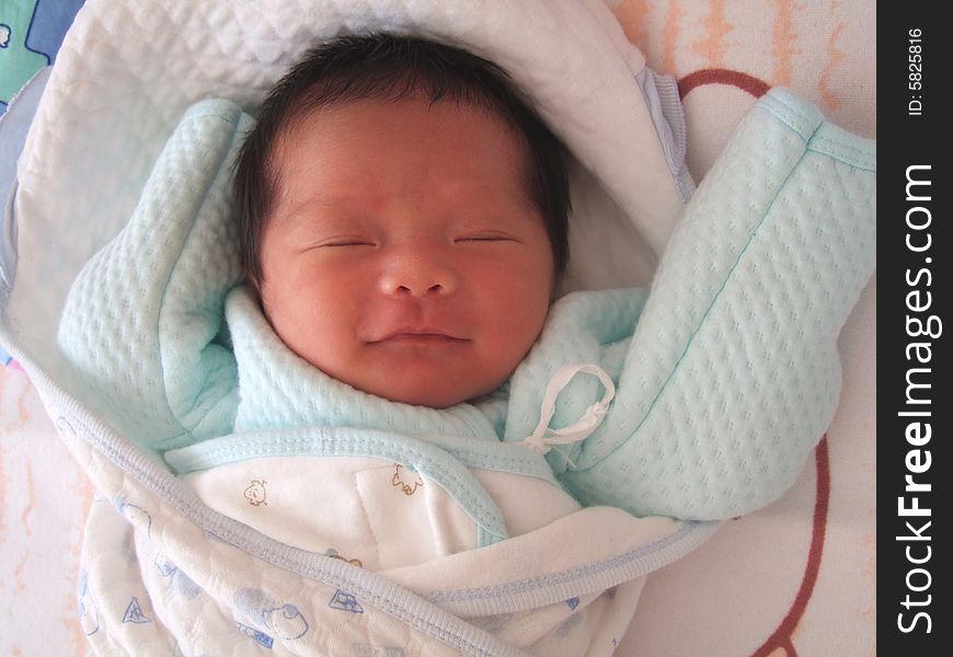 An infant is smiling while she is sleeping. An infant is smiling while she is sleeping