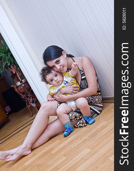 Young Mum With The Son Sit On A Floor Of A Room