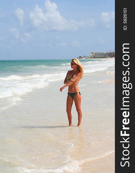 woman rubbing her arm while standing in the shallow beach water. woman rubbing her arm while standing in the shallow beach water