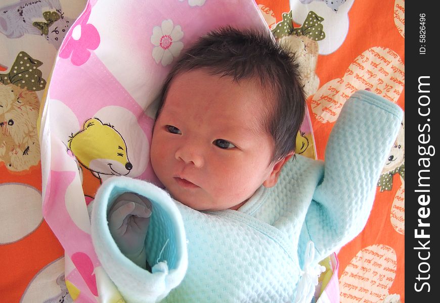 An infant on a bed facing the windows