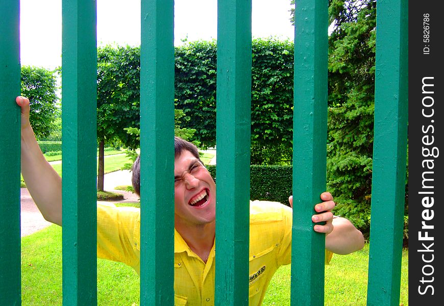 Photo of the young man behind a green fence.