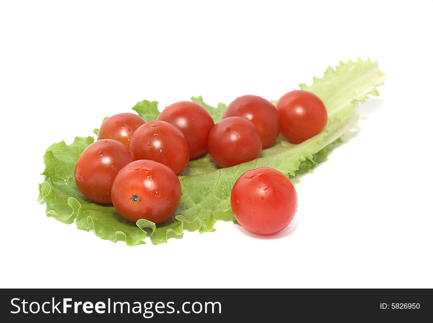 Tomatoes and a sheet of salad on a white background