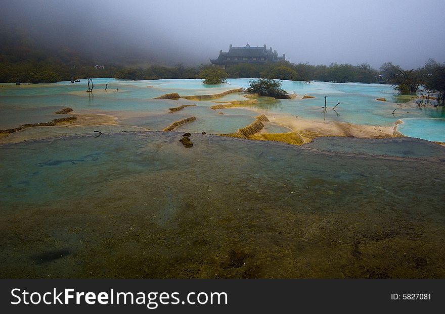 The color full pool in rain,with chinese temple in background,Huanglong scenic area,Sichuan,china. The color full pool in rain,with chinese temple in background,Huanglong scenic area,Sichuan,china