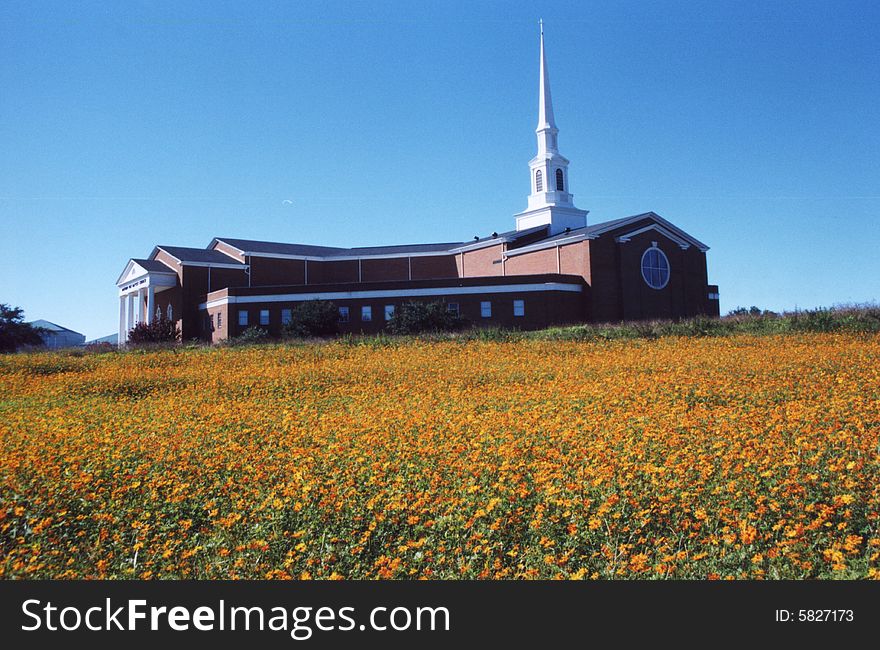 Photo of a church on a hill with orange flowers in the foreground. Photo of a church on a hill with orange flowers in the foreground.