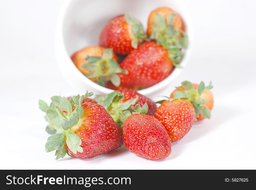 Strawberries pourring out of a bowl isolated on white