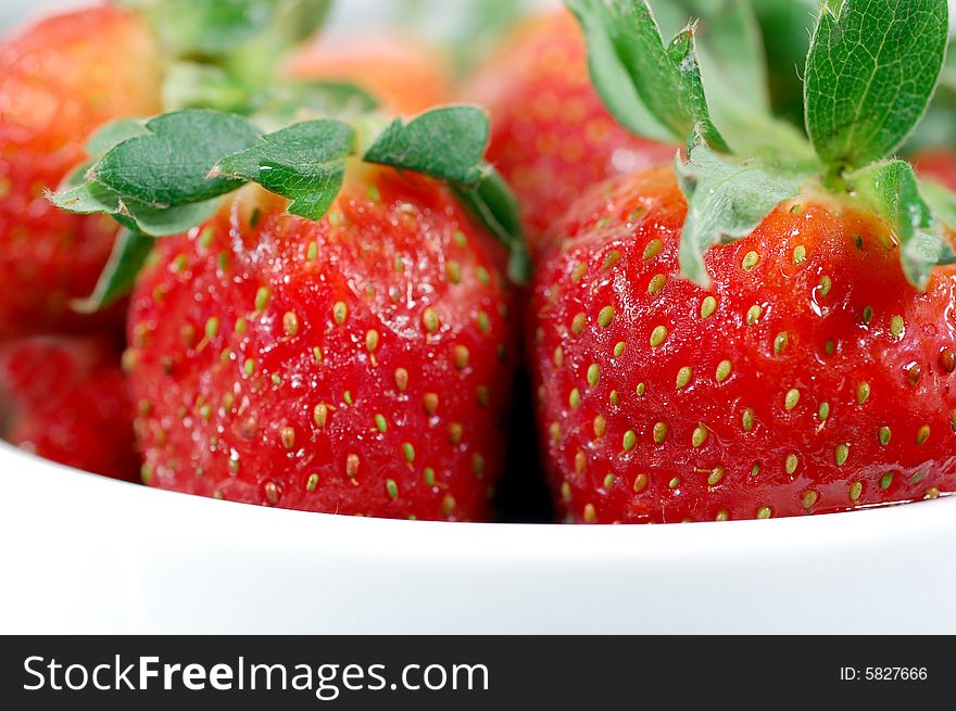 Macro shot of a group of strawberries in a white bowl. Macro shot of a group of strawberries in a white bowl