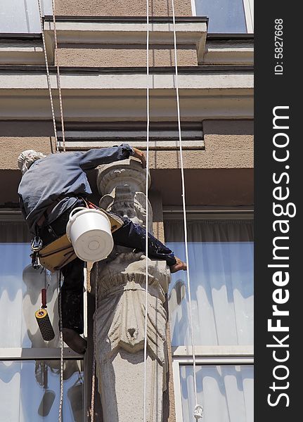 Washerman hangs on the rope and clean the window. Washerman hangs on the rope and clean the window