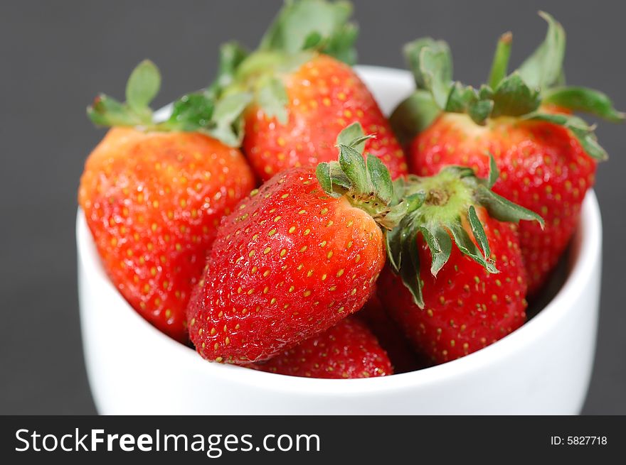 White bowl with strawberries isolated on a dark background