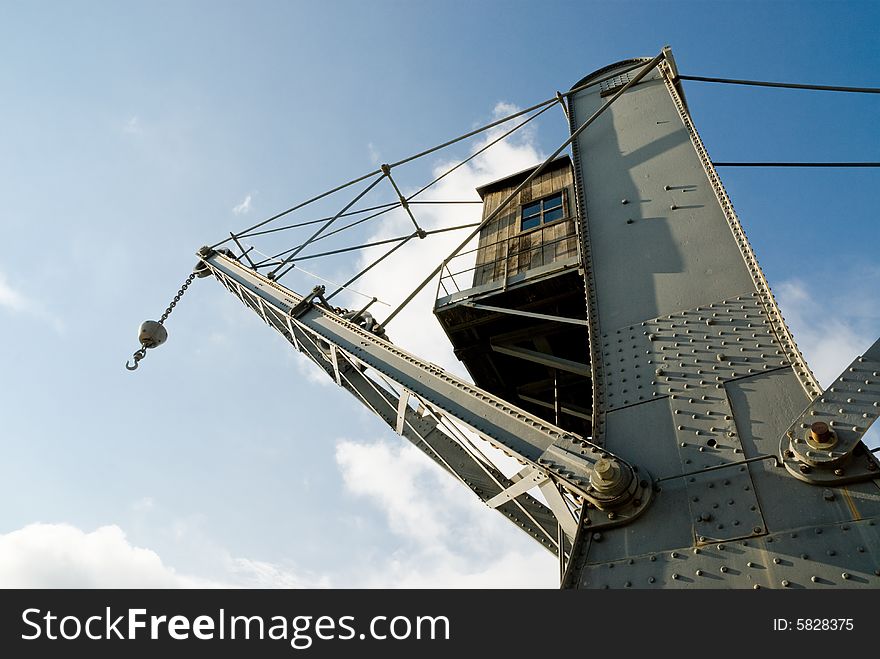 Ancient crane of 19th century against the blue sky. Ancient crane of 19th century against the blue sky