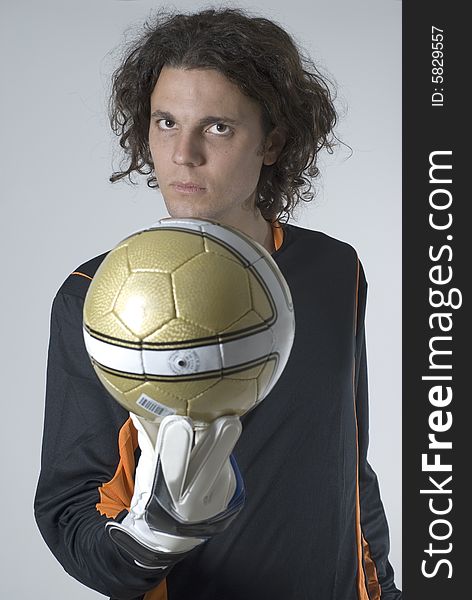 Man with a serious expression holds a soccer ball out in front of him. Vertically framed photograph. Man with a serious expression holds a soccer ball out in front of him. Vertically framed photograph.