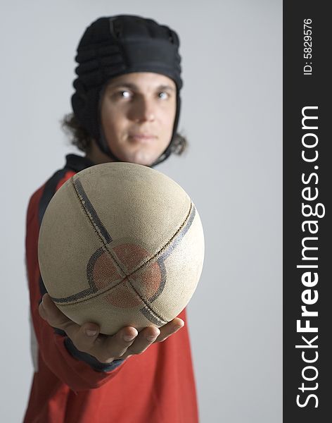 Rugby player wearing a helmet holds a football out in front of him. Vertically framed photograph. Rugby player wearing a helmet holds a football out in front of him. Vertically framed photograph.
