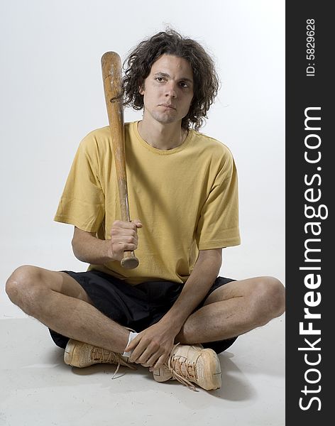Man sitting cross-legged holds a baseball bat and looks unhappy. Vertically framed photograph. Man sitting cross-legged holds a baseball bat and looks unhappy. Vertically framed photograph