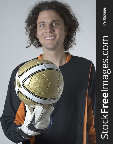 Soccer goalie wearing a jersey and gloves smiles as he holds a soccer ball. Vertically framed photograph. Soccer goalie wearing a jersey and gloves smiles as he holds a soccer ball. Vertically framed photograph
