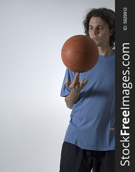 A male figure balancing a basketball on two fingers.  He is staring at the ball. Vertically framed shot. A male figure balancing a basketball on two fingers.  He is staring at the ball. Vertically framed shot.