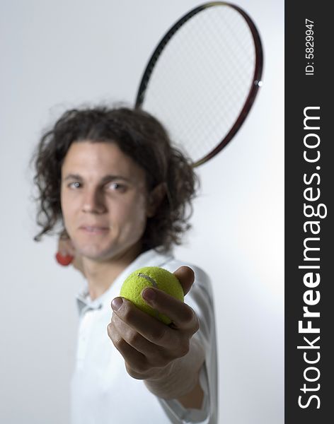 A young male serving a tennis ball.  He is looking at the camera, and he has a slight smile on his face.  Vertically framed shot. A young male serving a tennis ball.  He is looking at the camera, and he has a slight smile on his face.  Vertically framed shot.
