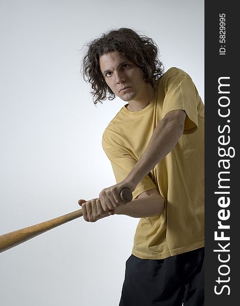 Man swings a baseball bat and wears an angry expression on his face. Vertically framed photograph. Man swings a baseball bat and wears an angry expression on his face. Vertically framed photograph