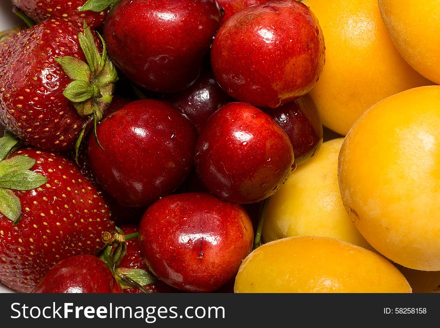 Fresh ripe apricot, cherry and strawberry close up background.