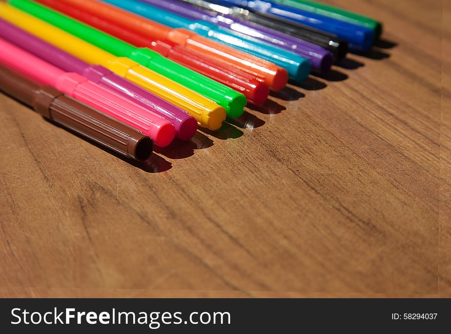 Colored markers on wooden table closeup