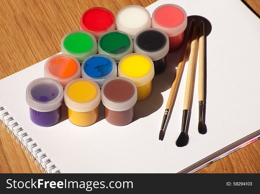 Set of watercolor paints and brushes with white notepad