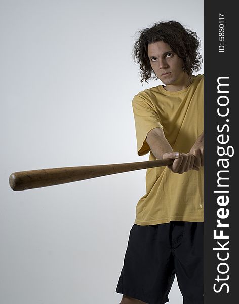 Man swings a baseball bat and wears an angry expression on his face. Vertically framed photograph. Man swings a baseball bat and wears an angry expression on his face. Vertically framed photograph