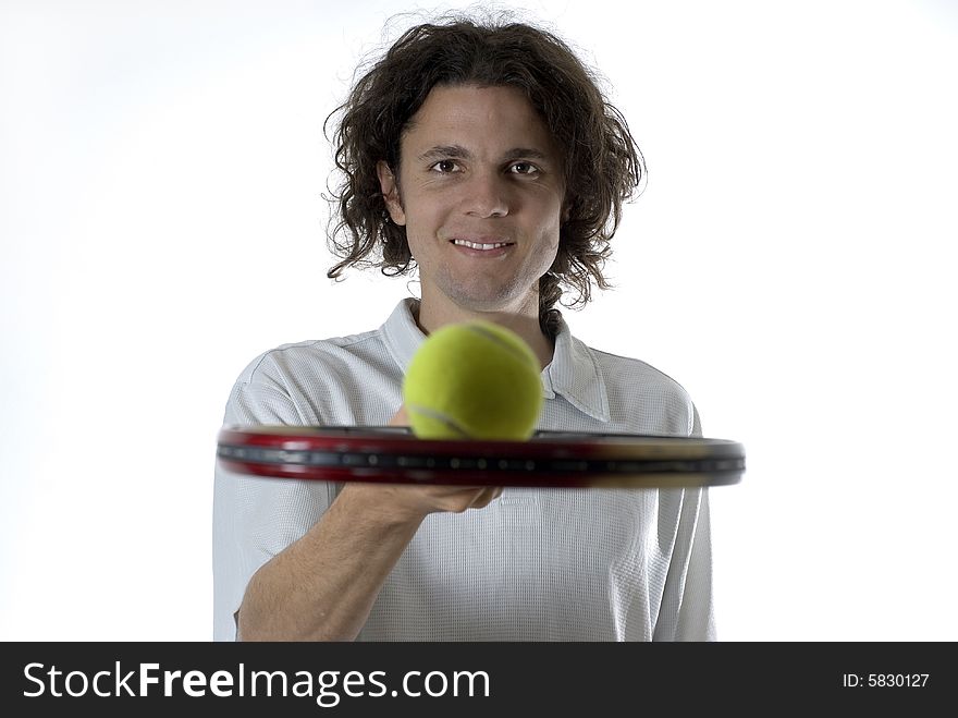 Man with a smile on his face holds a tennis racket and balances a tennis ball on top of it. Horizontally framed photograph. Man with a smile on his face holds a tennis racket and balances a tennis ball on top of it. Horizontally framed photograph