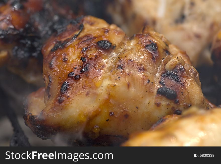 Chicken pieces being grilled on charcoals of hibachi grill. Chicken pieces being grilled on charcoals of hibachi grill.