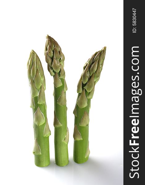 Three asparagus spears standing over white backgrond with light shadow