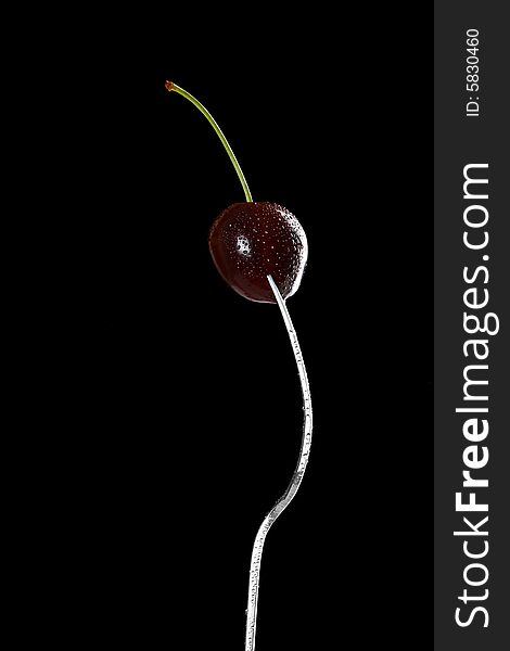 Wet cherry with fork over black background, refined curves design