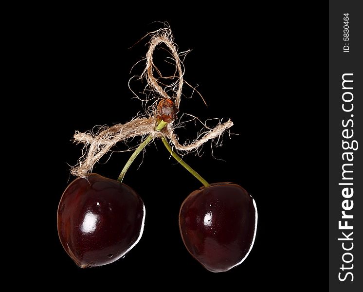 Two cherryes tied by rope, over black background. Two cherryes tied by rope, over black background