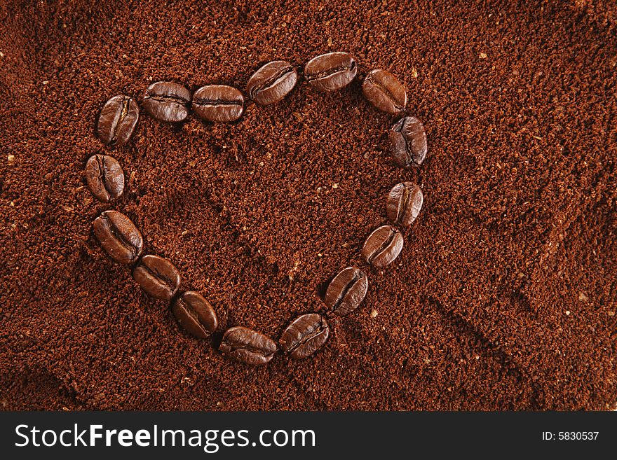 Coffee beans in heart shape and ground background