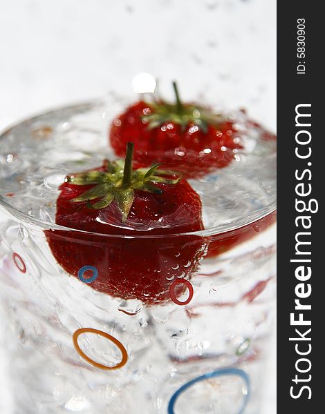 Water glass ice cube and strawberries with waterdrops on background, close-up, shallow FOF