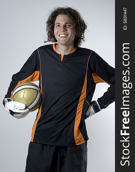 Goalie holding a soccer ball.  He is smiling and looking at the camera.  Vertically framed shot. Goalie holding a soccer ball.  He is smiling and looking at the camera.  Vertically framed shot.