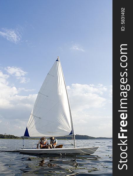 A man and a woman are sailing a sailboat on a lake.  Vertically framed shot. A man and a woman are sailing a sailboat on a lake.  Vertically framed shot.