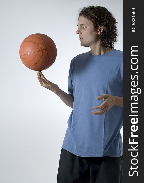 Man concentrates while balancing a basketball on his finger - Vertically framed photograph. Man concentrates while balancing a basketball on his finger - Vertically framed photograph