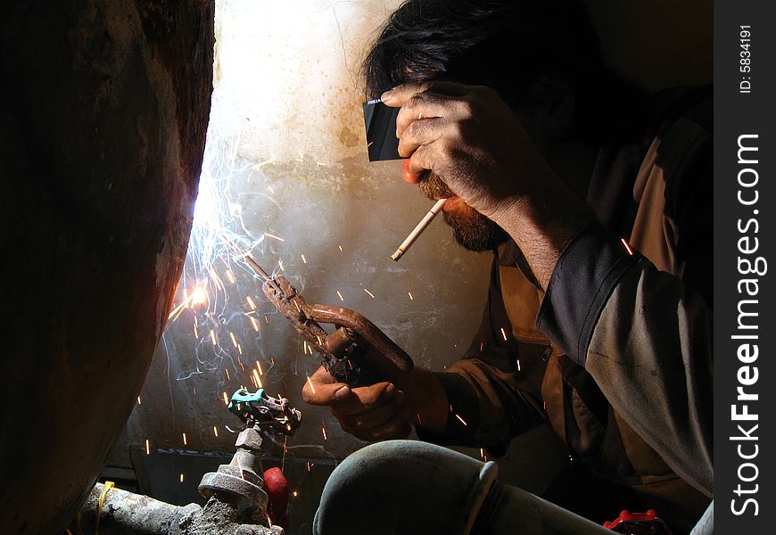 Smoking welder at work without complete protective tools