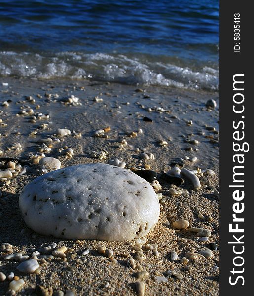 A white rock at the shoreline with waves